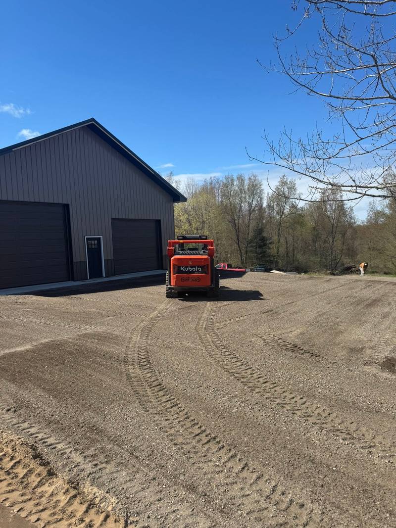 Track loader grading the yard in front of a new pole barn