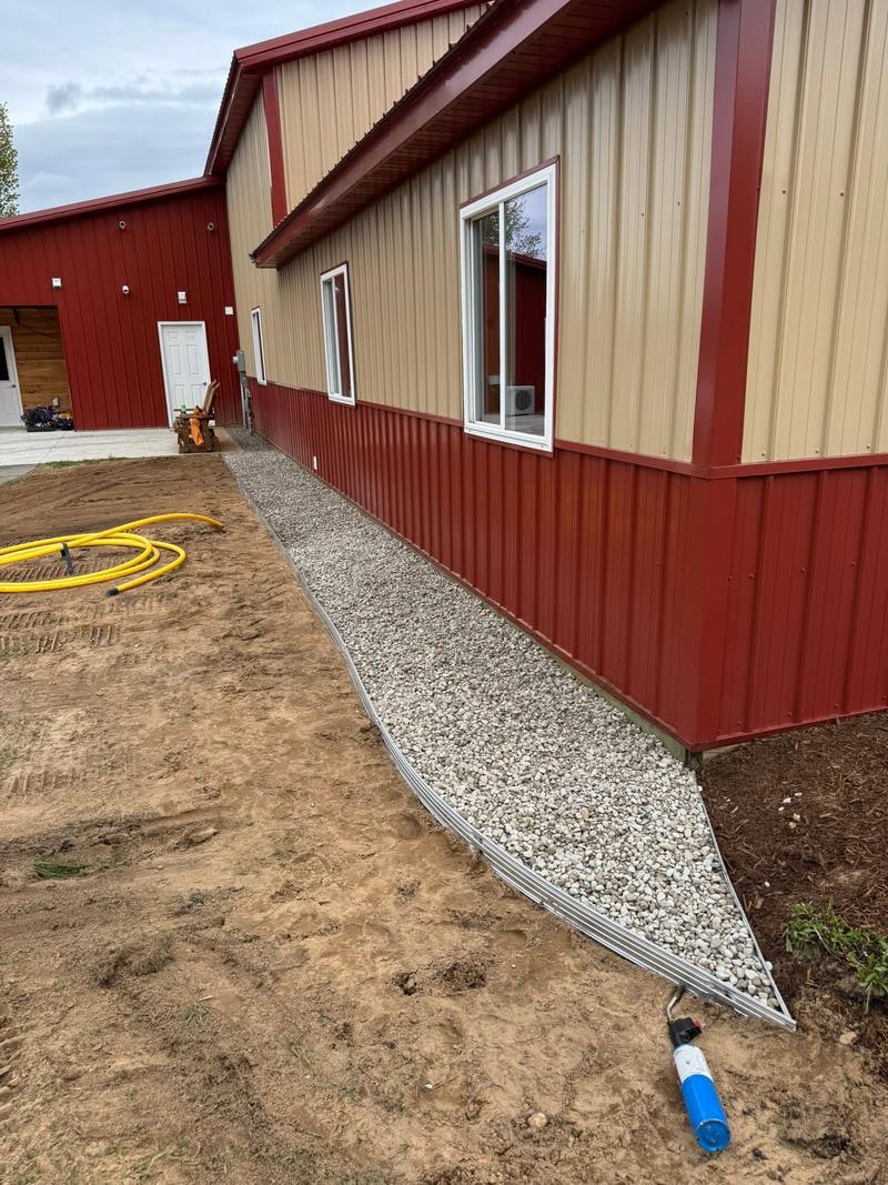 New crushed stone drip edge along a two-tone pole barn